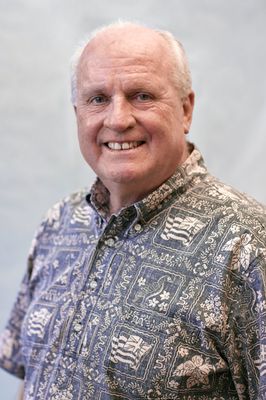 A man in a hawaiian shirt is smiling for the camera.