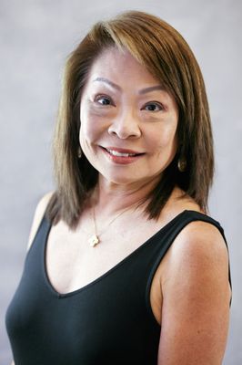 A woman in a black tank top is smiling for the camera.