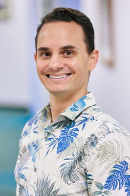 A man in a hawaiian shirt is smiling for the camera.