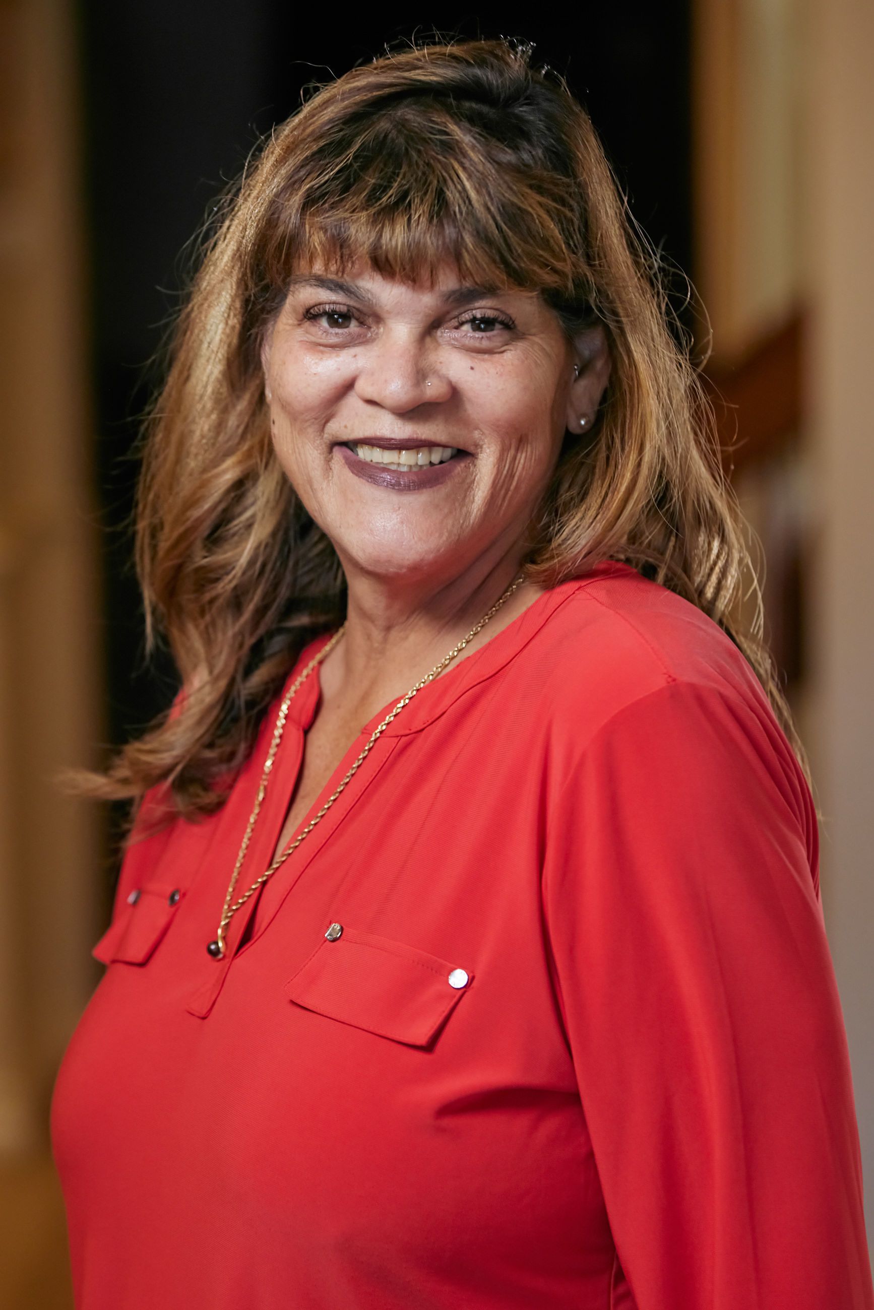 A woman in a red shirt is smiling for the camera.