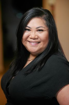 A woman in a black shirt is smiling for the camera.