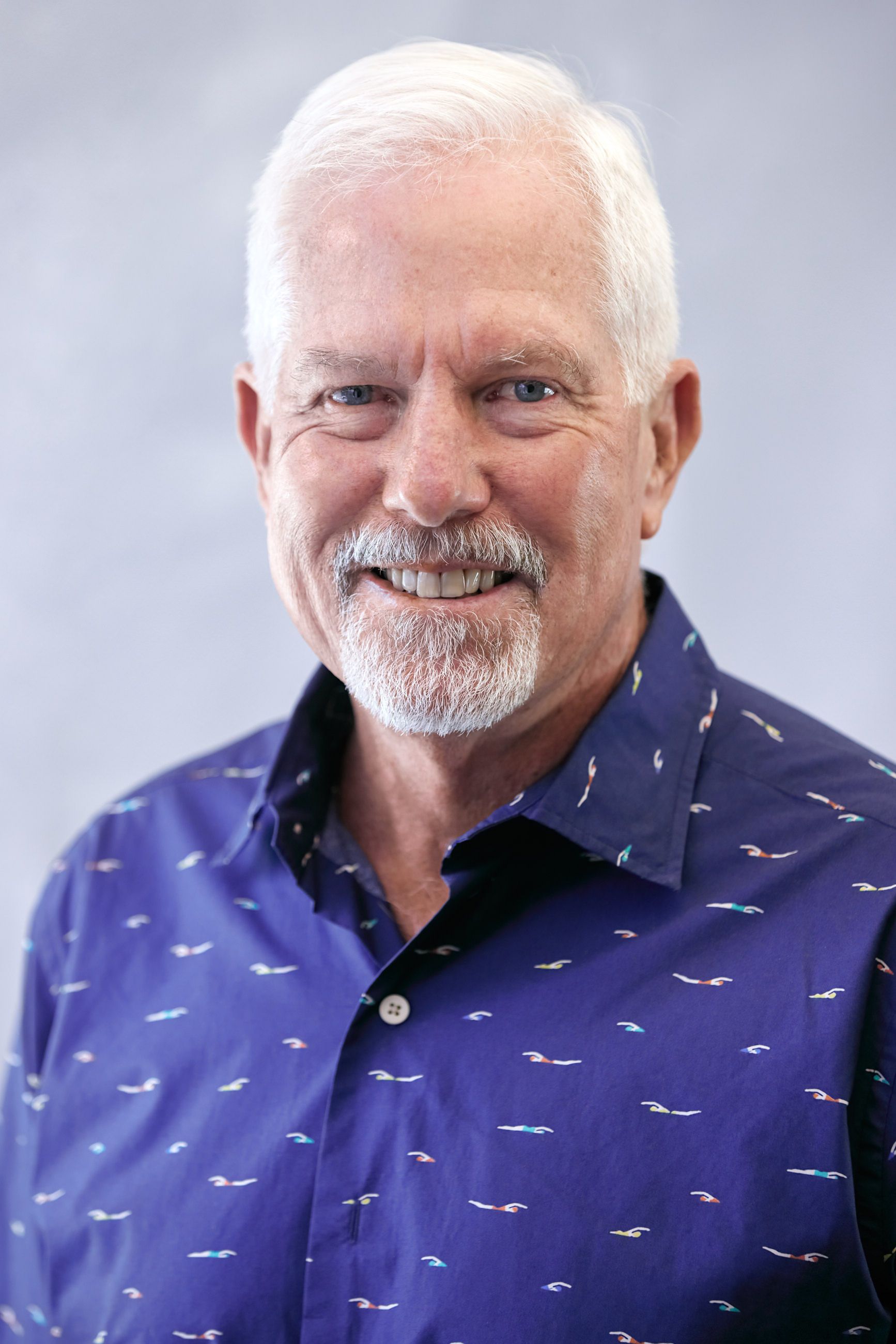 A man with a beard and a blue shirt is smiling for the camera.