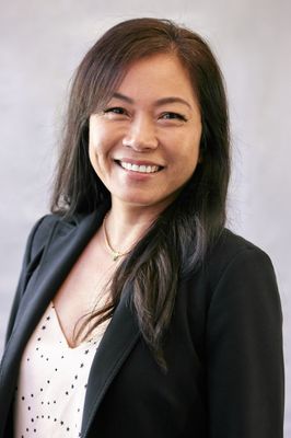 A woman in a black jacket and white shirt is smiling for the camera.