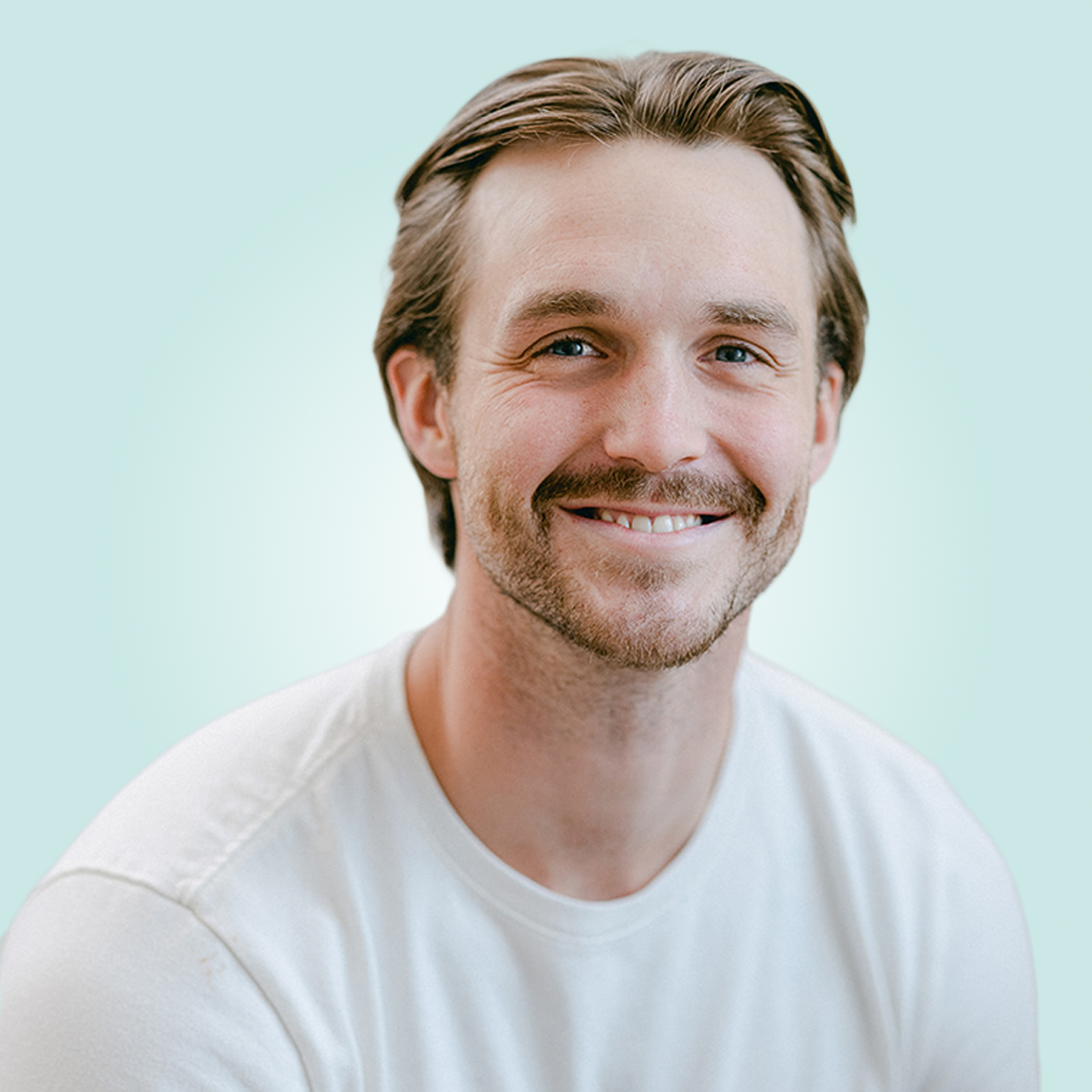 A man with a beard is smiling and wearing a white shirt