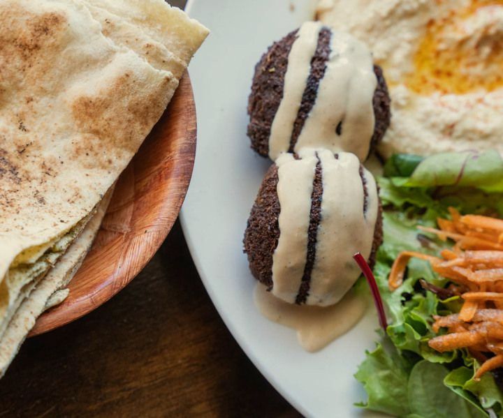 a plate of food with falafel and hummus next to a plate of pita bread