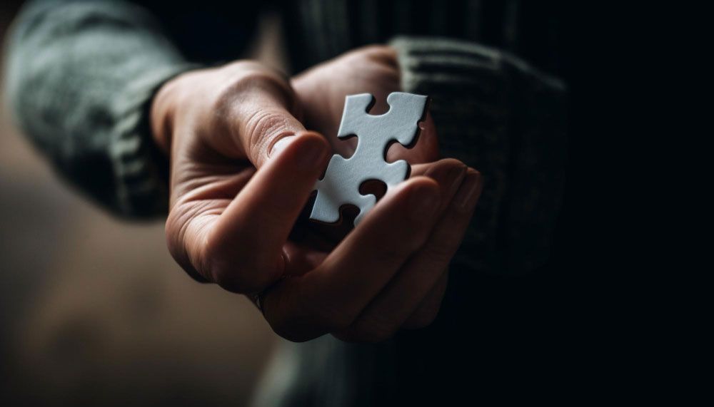 A person is holding a piece of a puzzle in their hands.