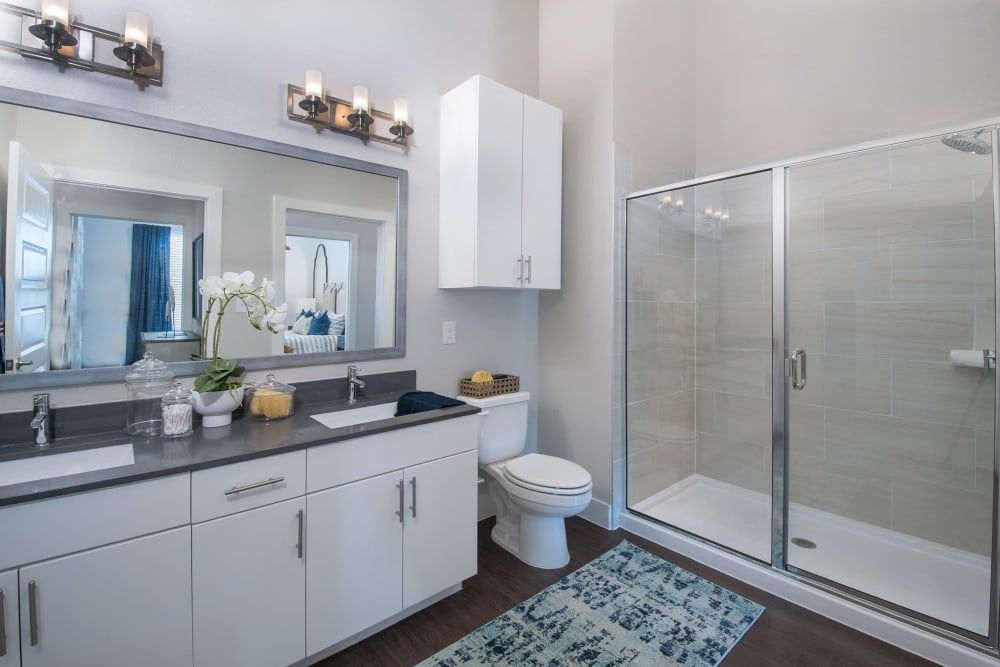 A bathroom with a toilet , sink , mirror and walk in shower at Marquis Dominion in San Antonio, TX. 
