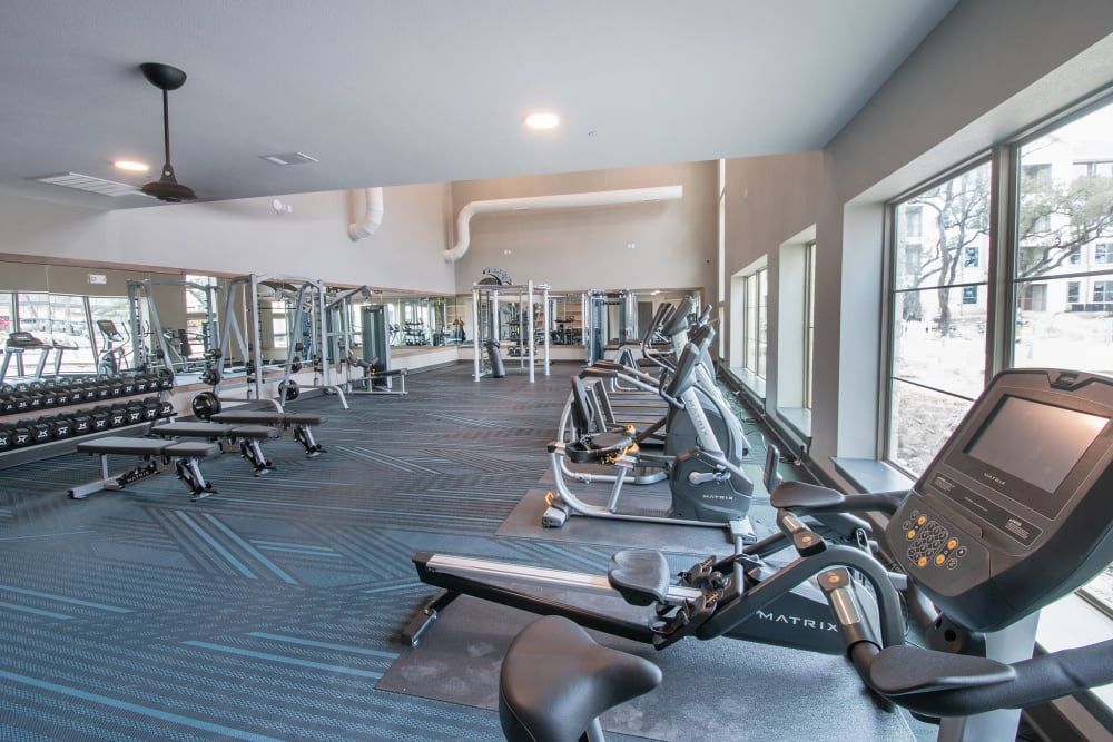 A large gym with a lot of exercise equipment and a ceiling fan at Marquis Dominion in San Antonio, TX. 