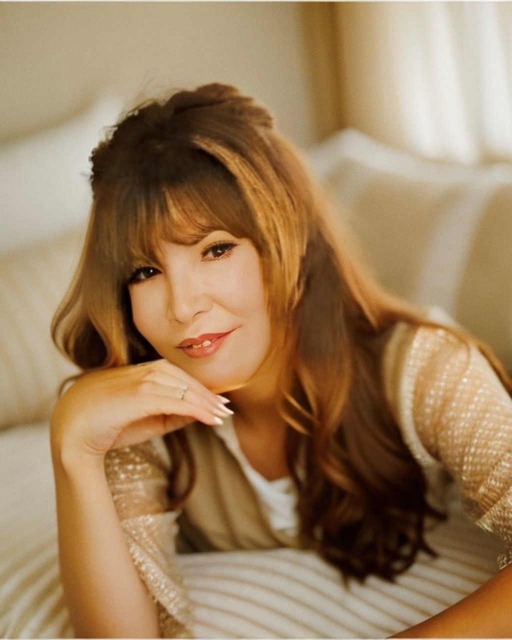 A woman laying on a bed with her hand on her chin