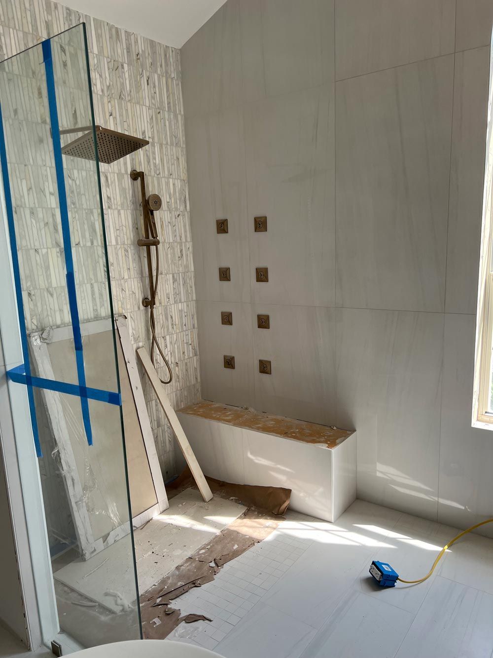A bathroom under construction with a walk in shower and a bench.
