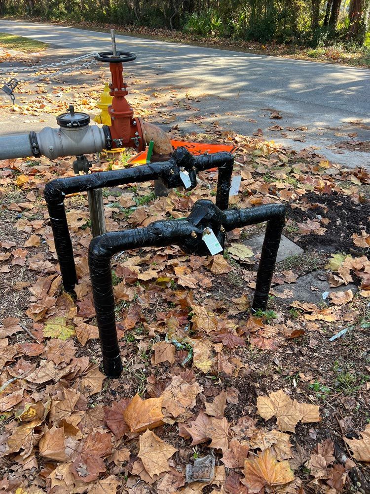 A couple of pipes sitting on top of a pile of leaves next to a road.
