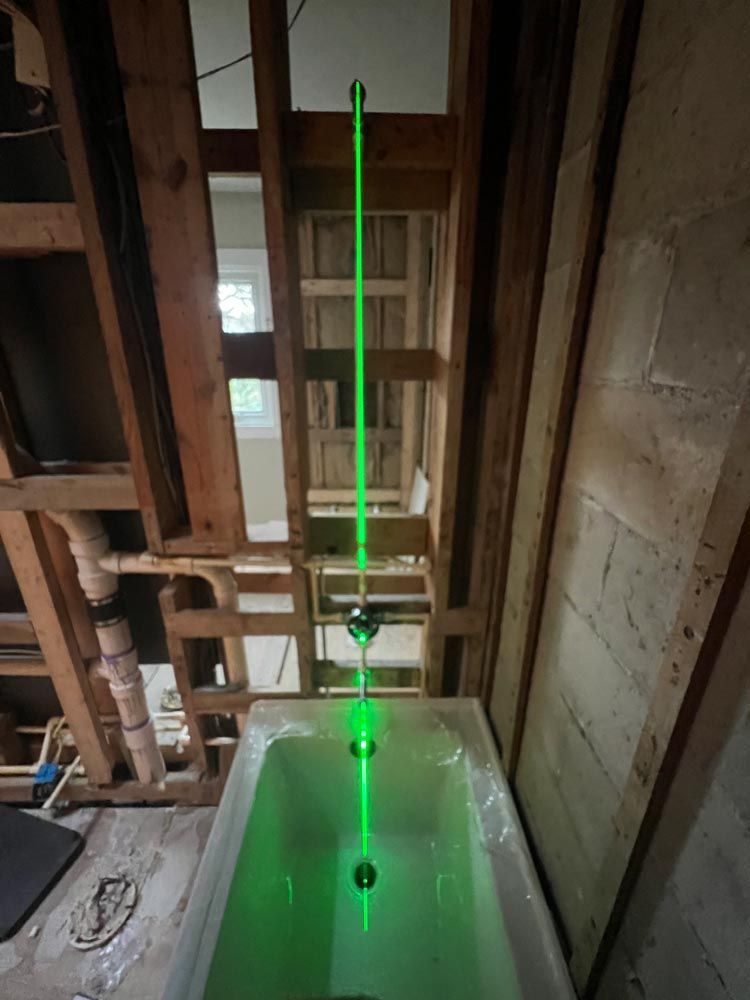 A green laser is shining on a bathtub in a bathroom under construction.