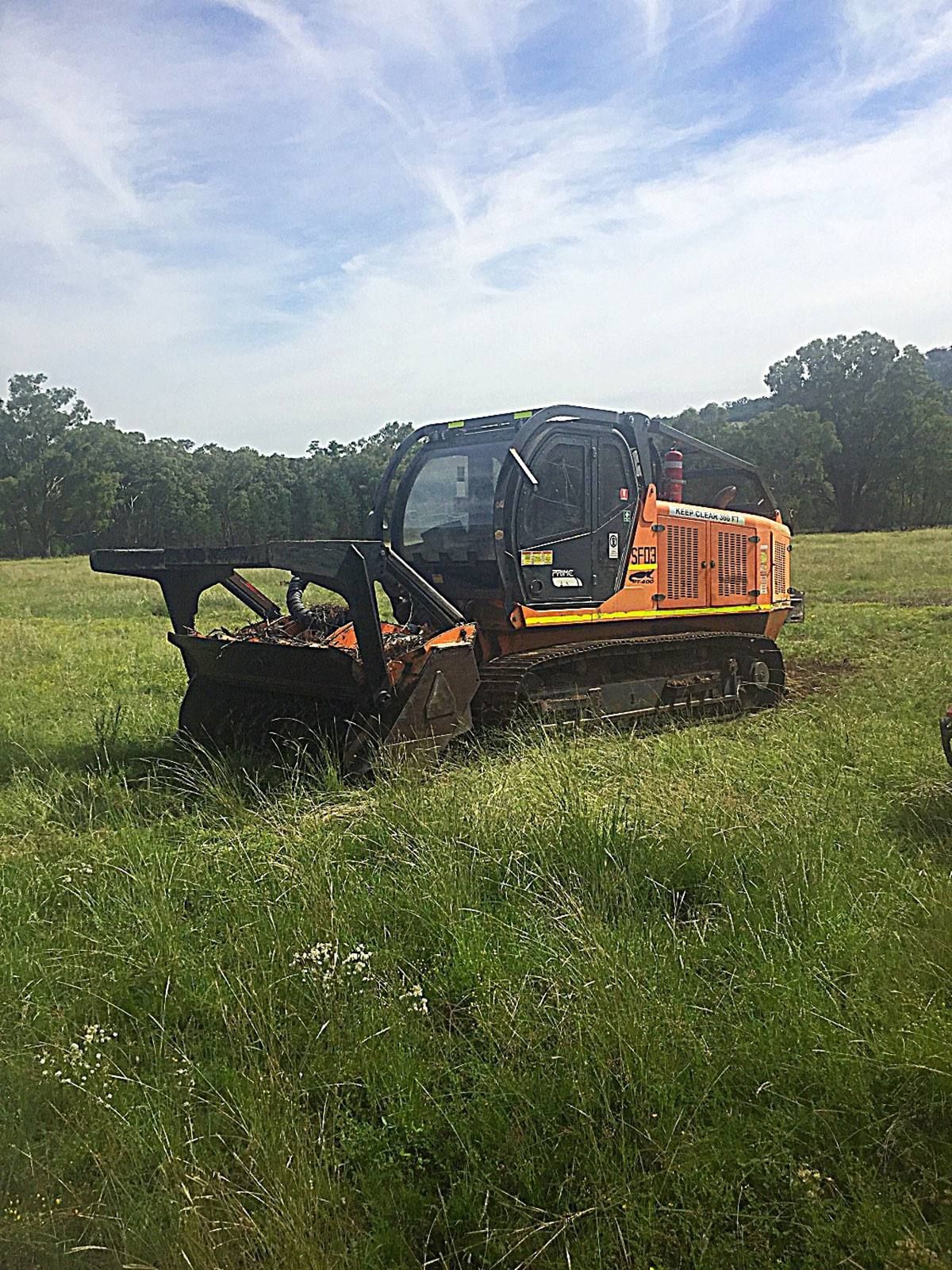 A bulldozer is driving through a grassy field.