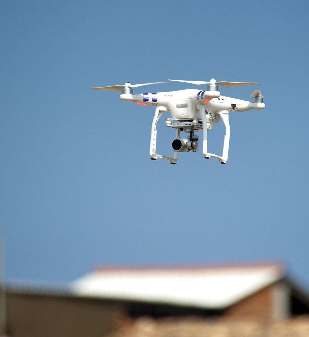 A drone with a camera attached to it is flying over a building