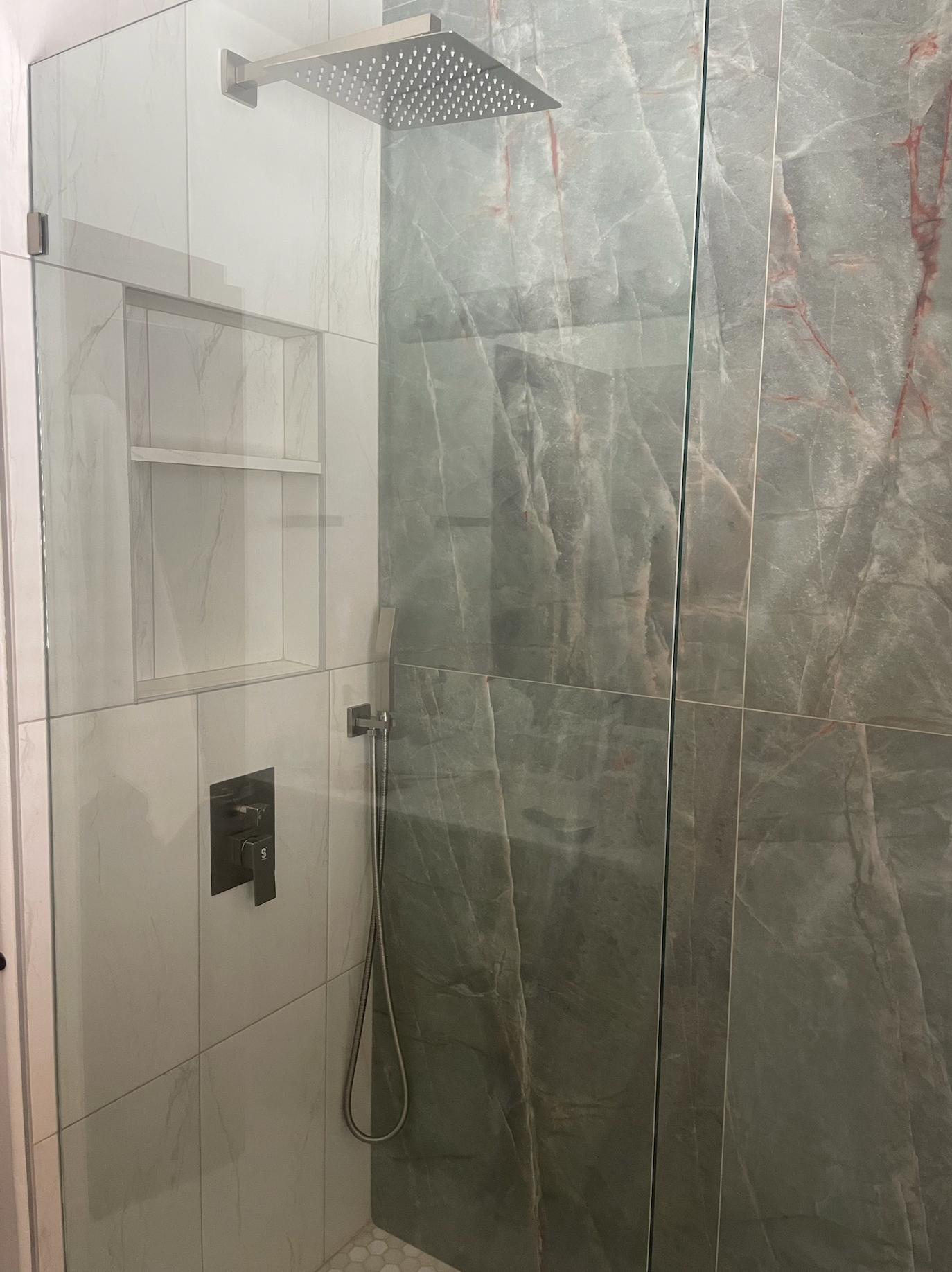 A bathroom with a walk in shower and a shower head.