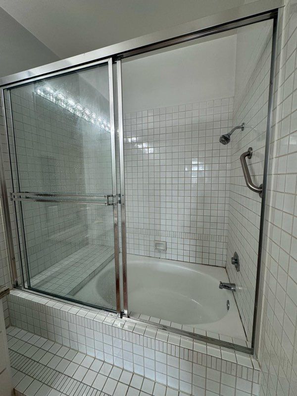 There is a bathtub in the bathroom with a glass shower door.
