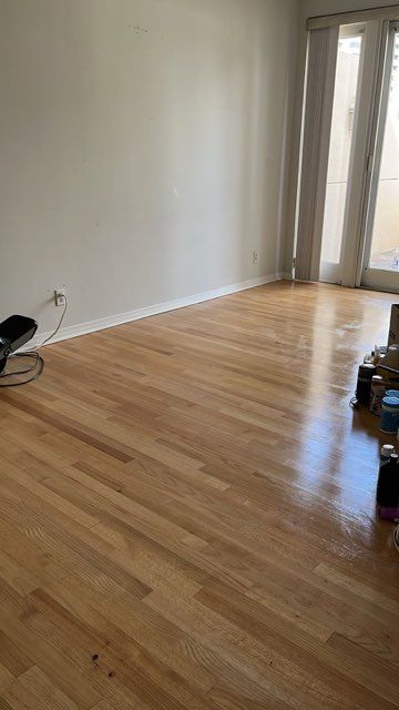 An empty living room with hardwood floors and white walls.