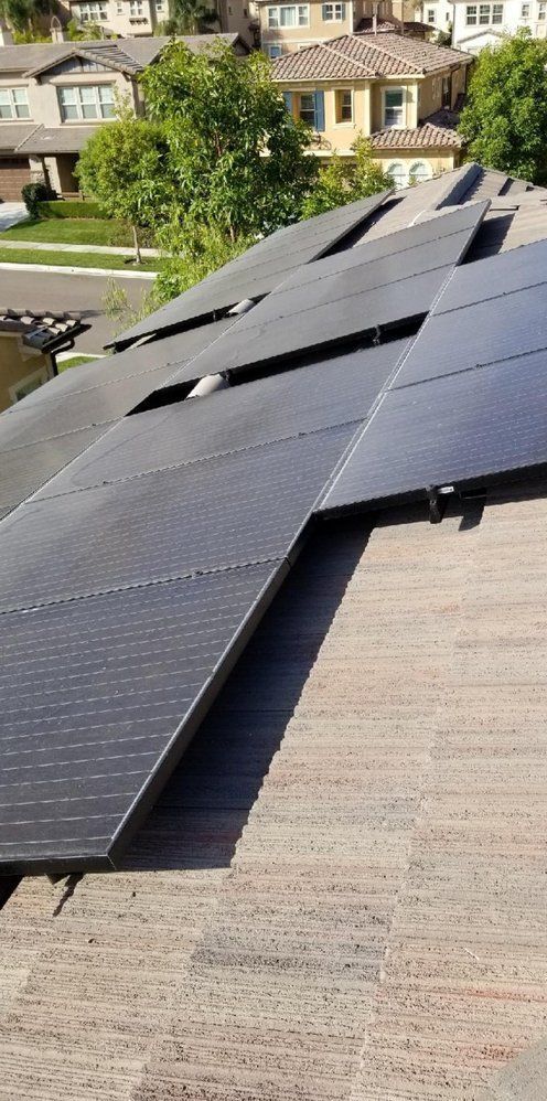 There are many solar panels on the roof of a house.