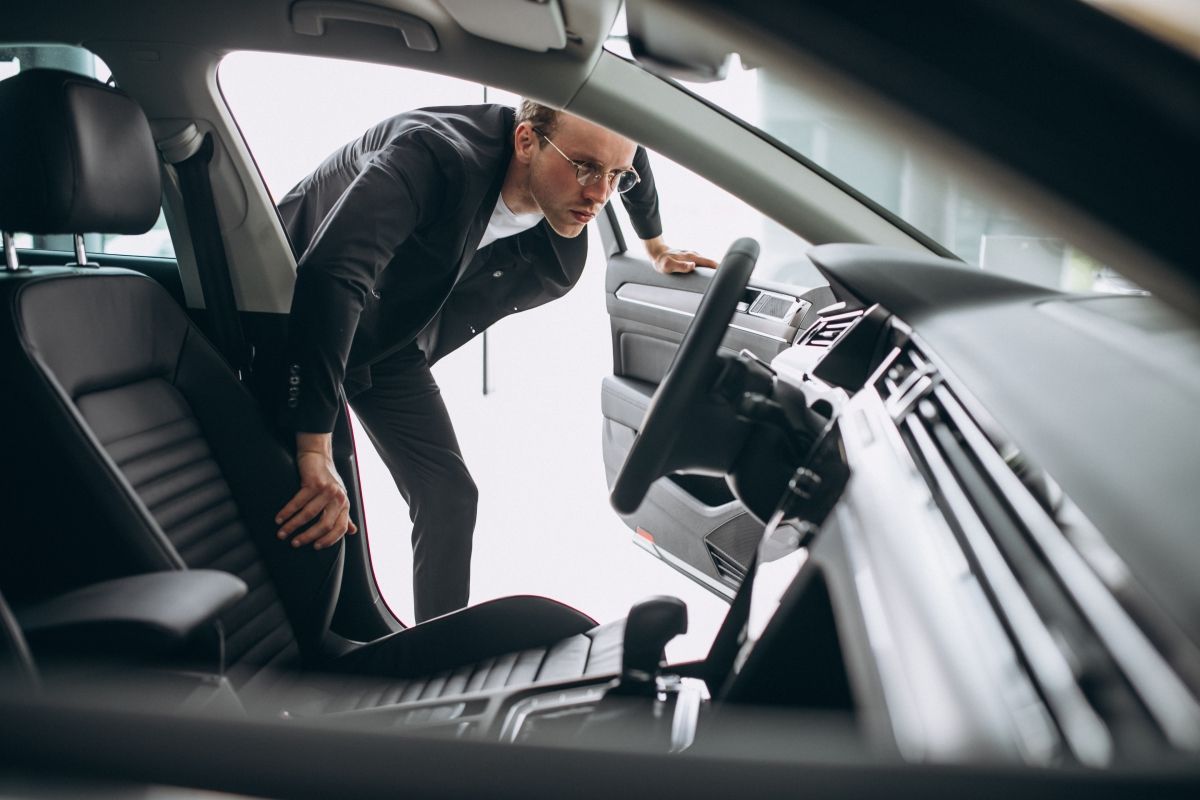 A man is looking into the interior of a car.
