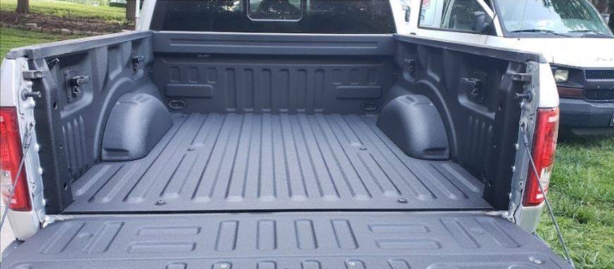 The back of a truck with the bed open is painted black.