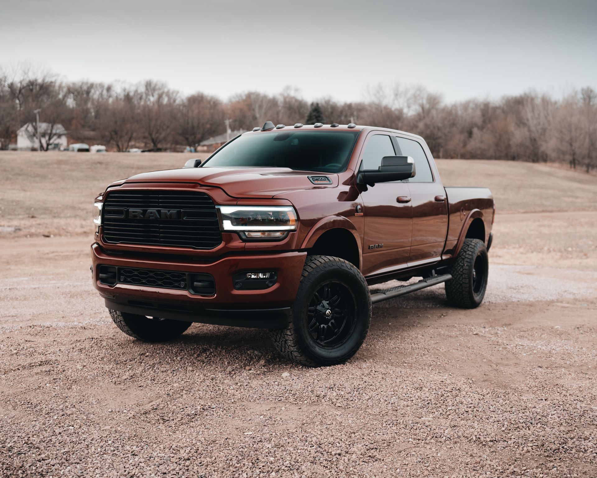 A red ram truck is parked in a dirt field.
