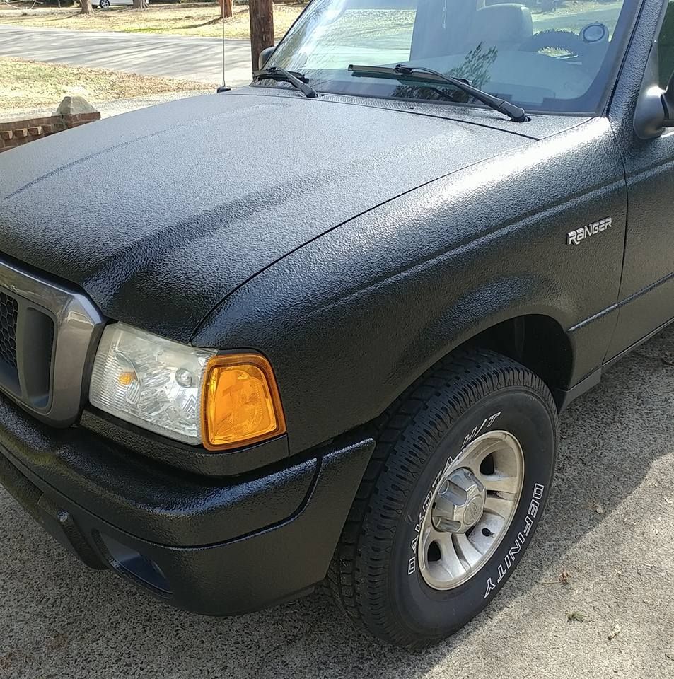 A black ford ranger is parked on the side of the road