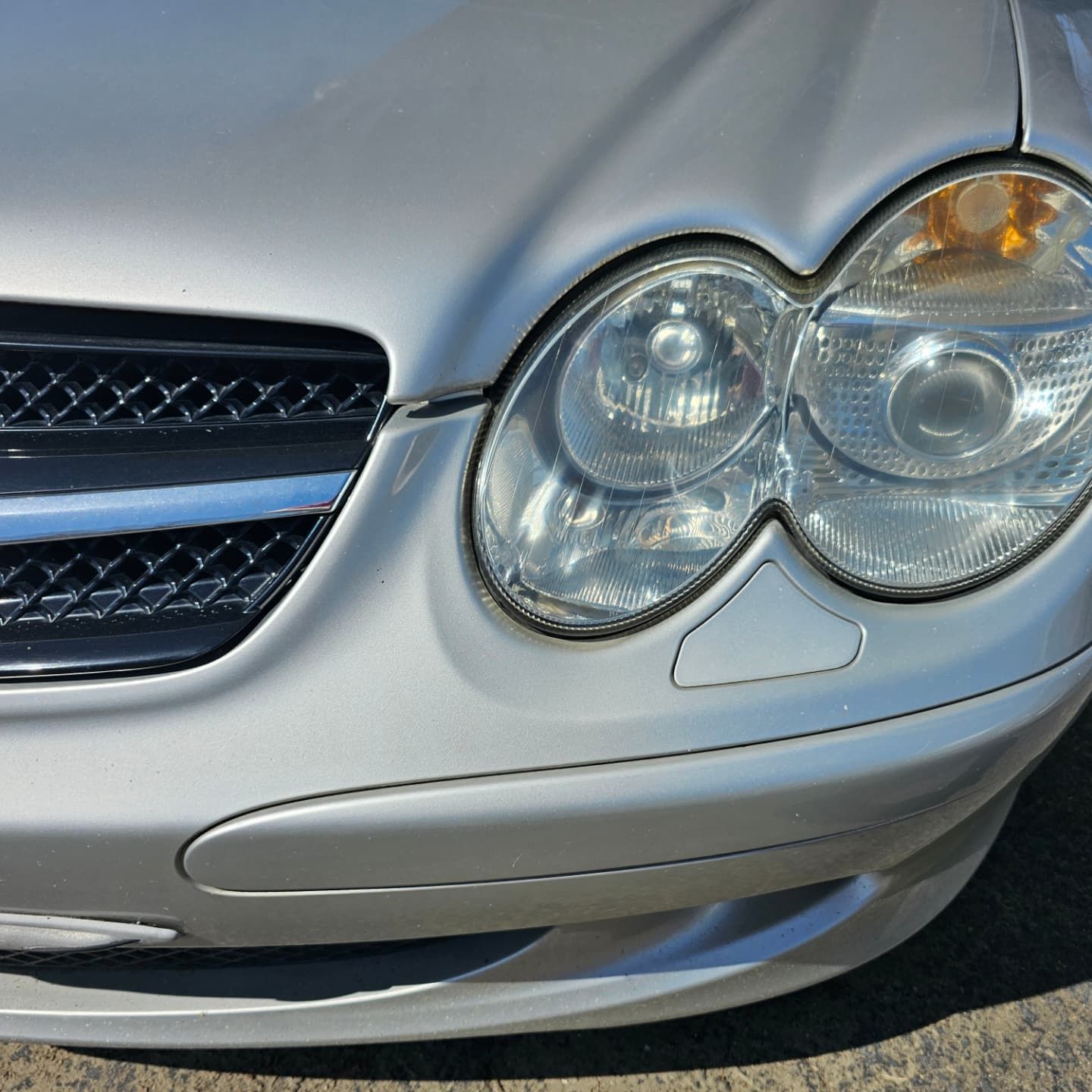 Silver car front: headlights, grille, and bumper.