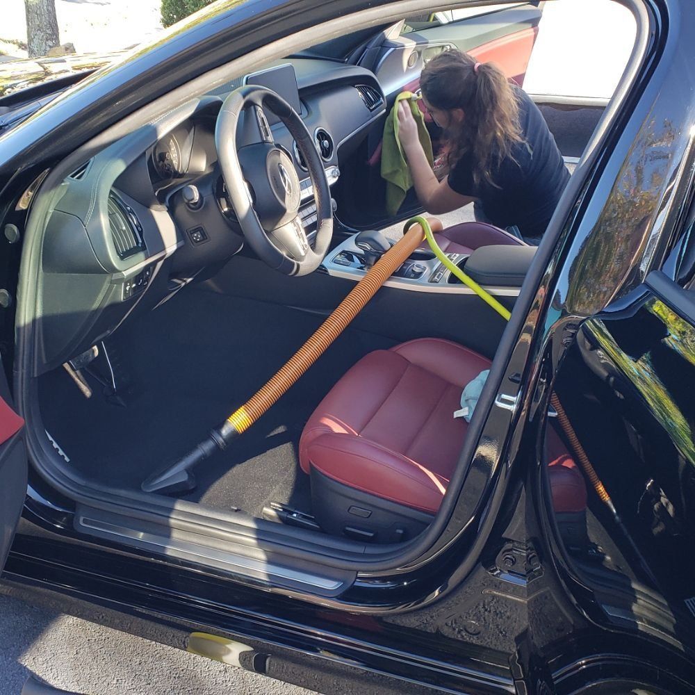 A woman is cleaning the interior of a black car