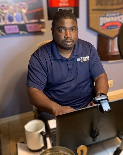 A man in a blue shirt is sitting in front of a computer