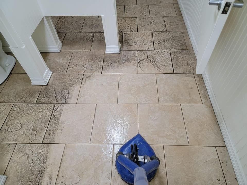 A person is cleaning a tile floor with a vacuum cleaner.