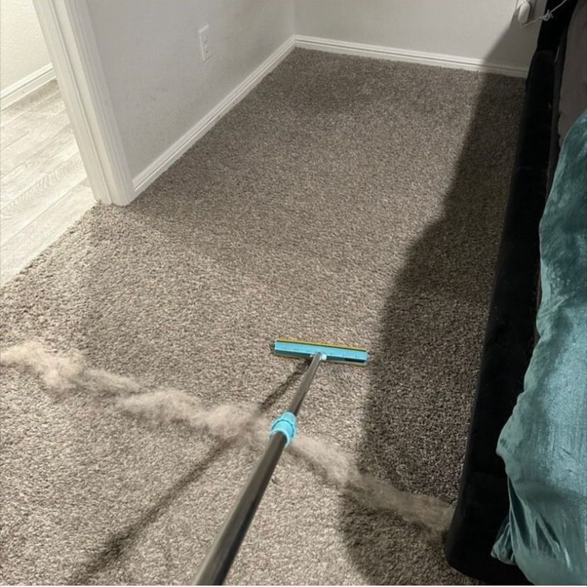 A person is sweeping a carpet with a broom.