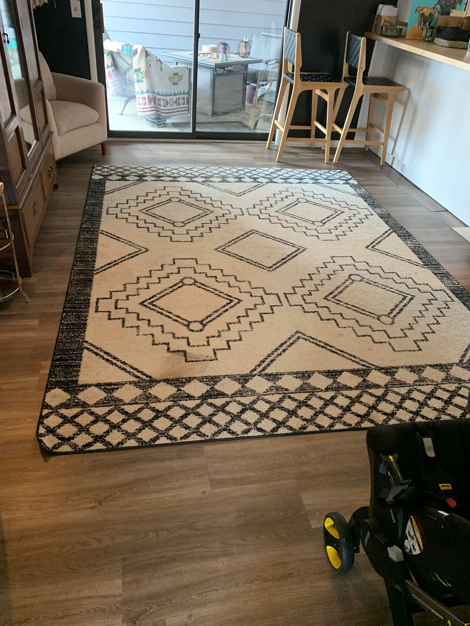 A large rug is sitting on a wooden floor in a living room.