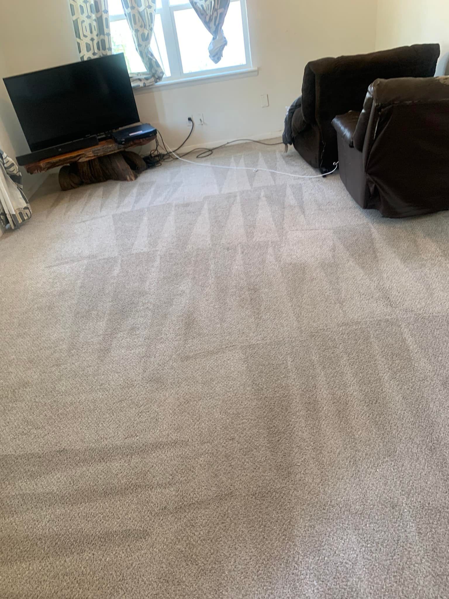 A living room with a couch , chair , television and carpet.