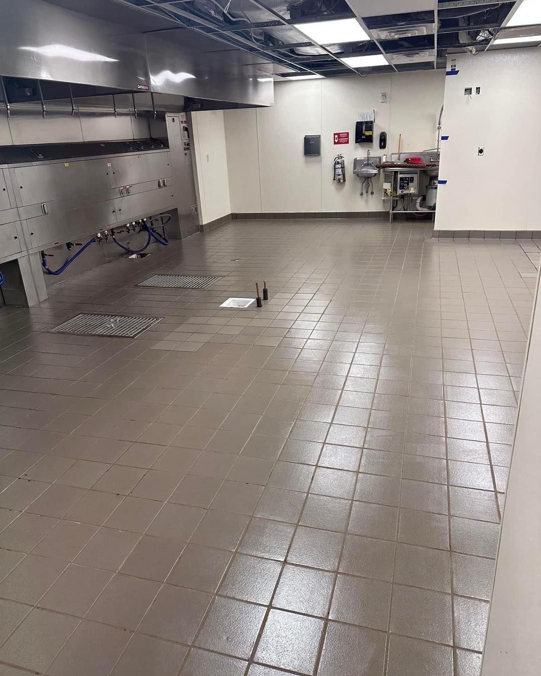An empty kitchen with a tiled floor and stainless steel appliances.