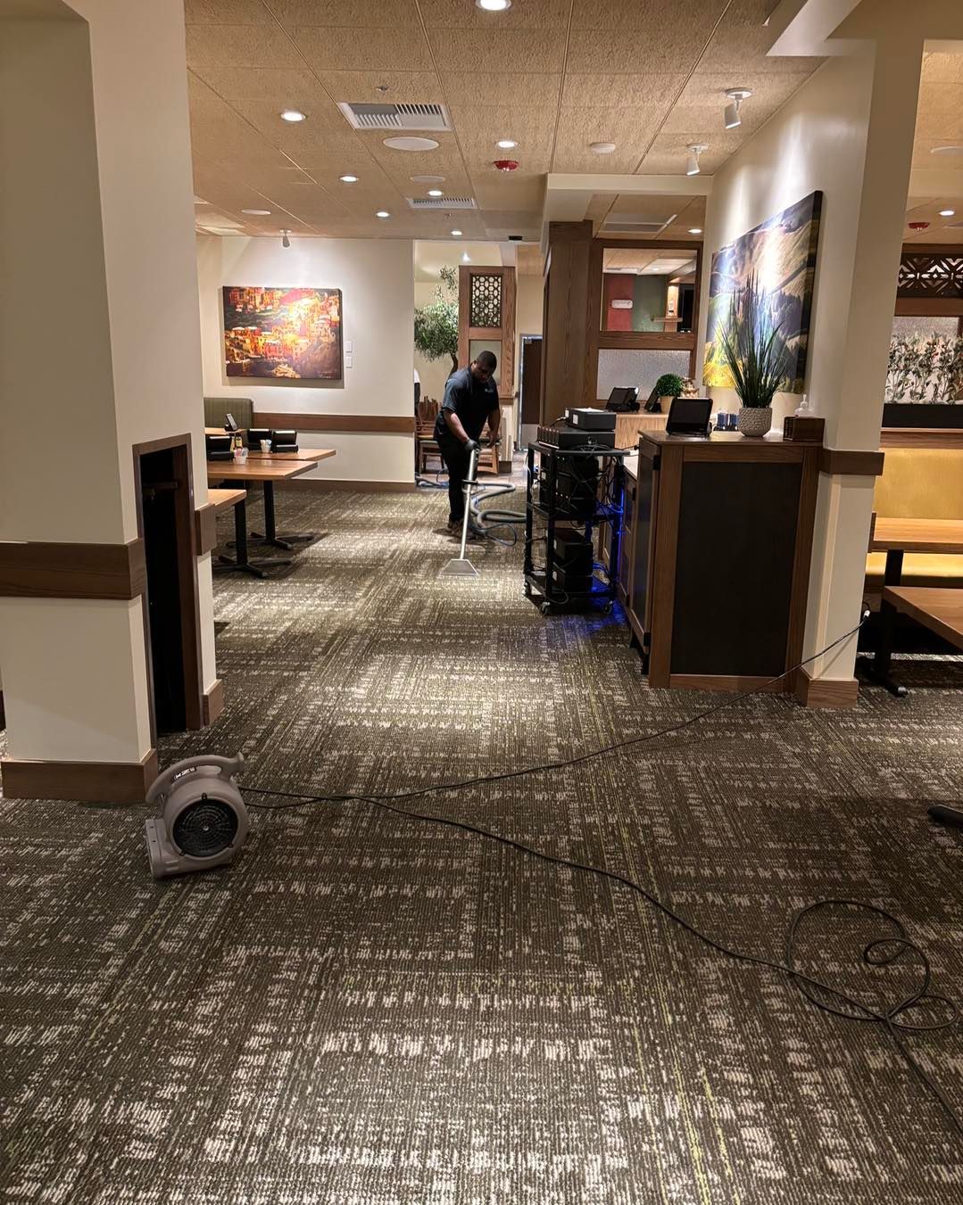 A man is vacuuming the floor of a restaurant.