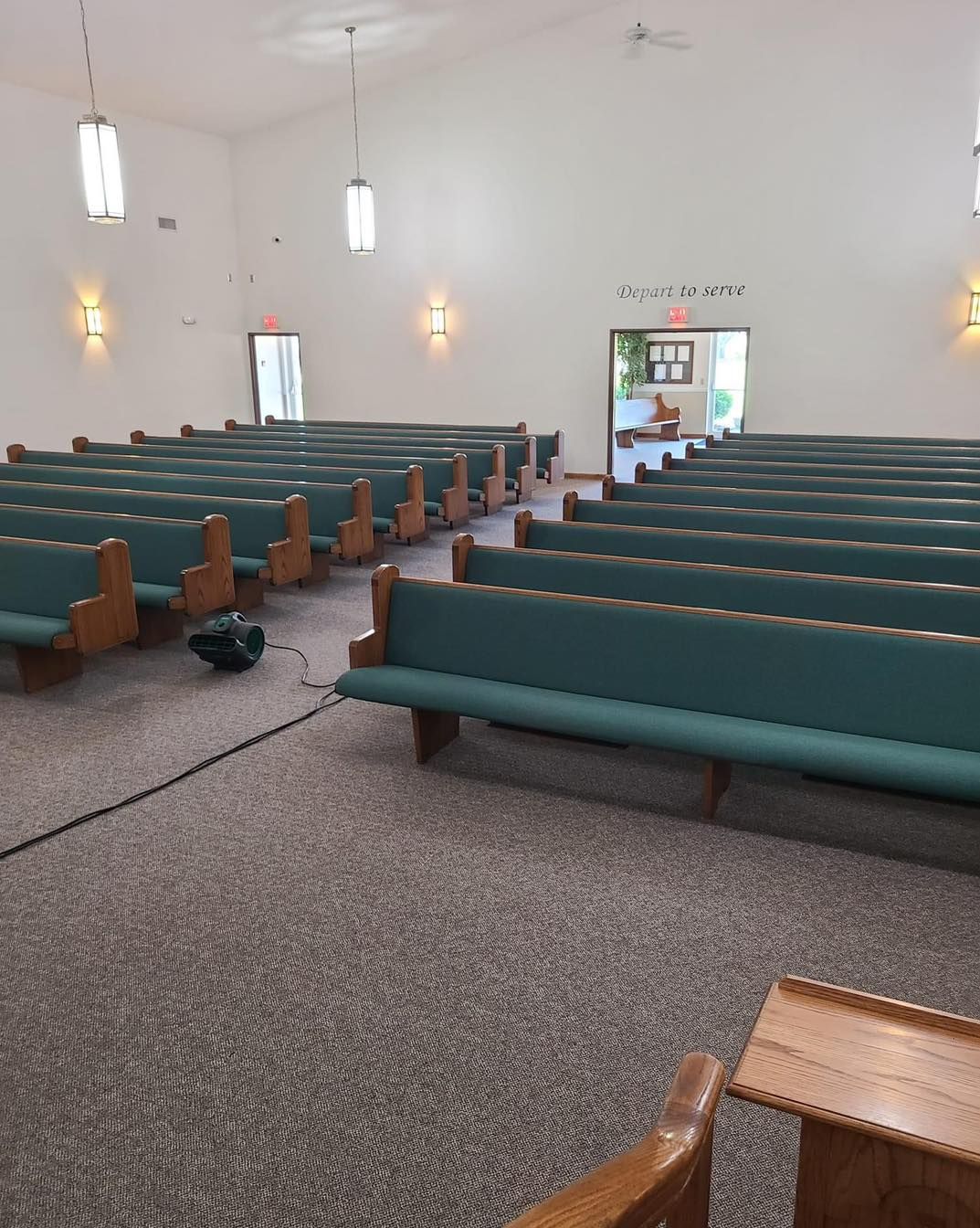 A church with rows of green benches and a podium