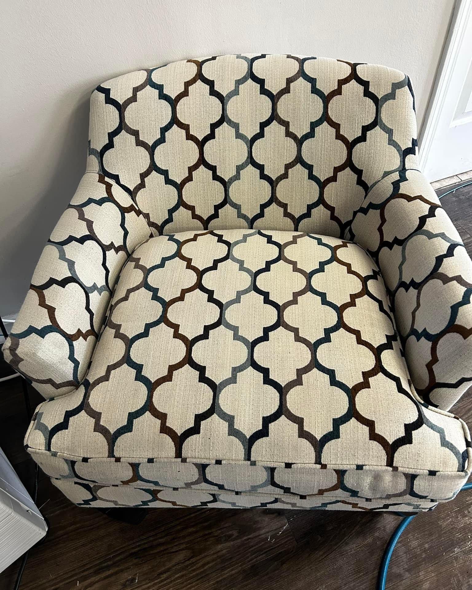 A chair with a pattern on it is sitting on a wooden floor.