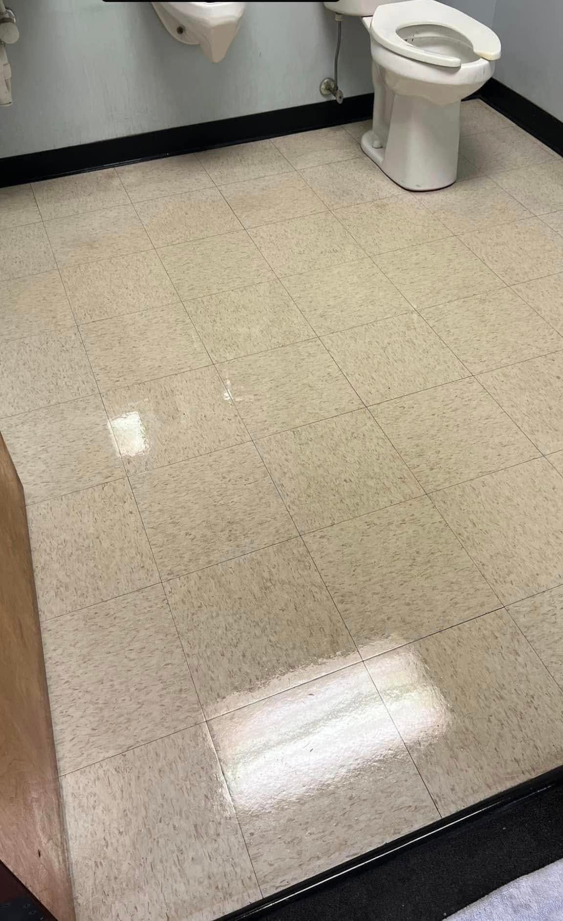 A toilet is sitting on a tiled floor in a bathroom.