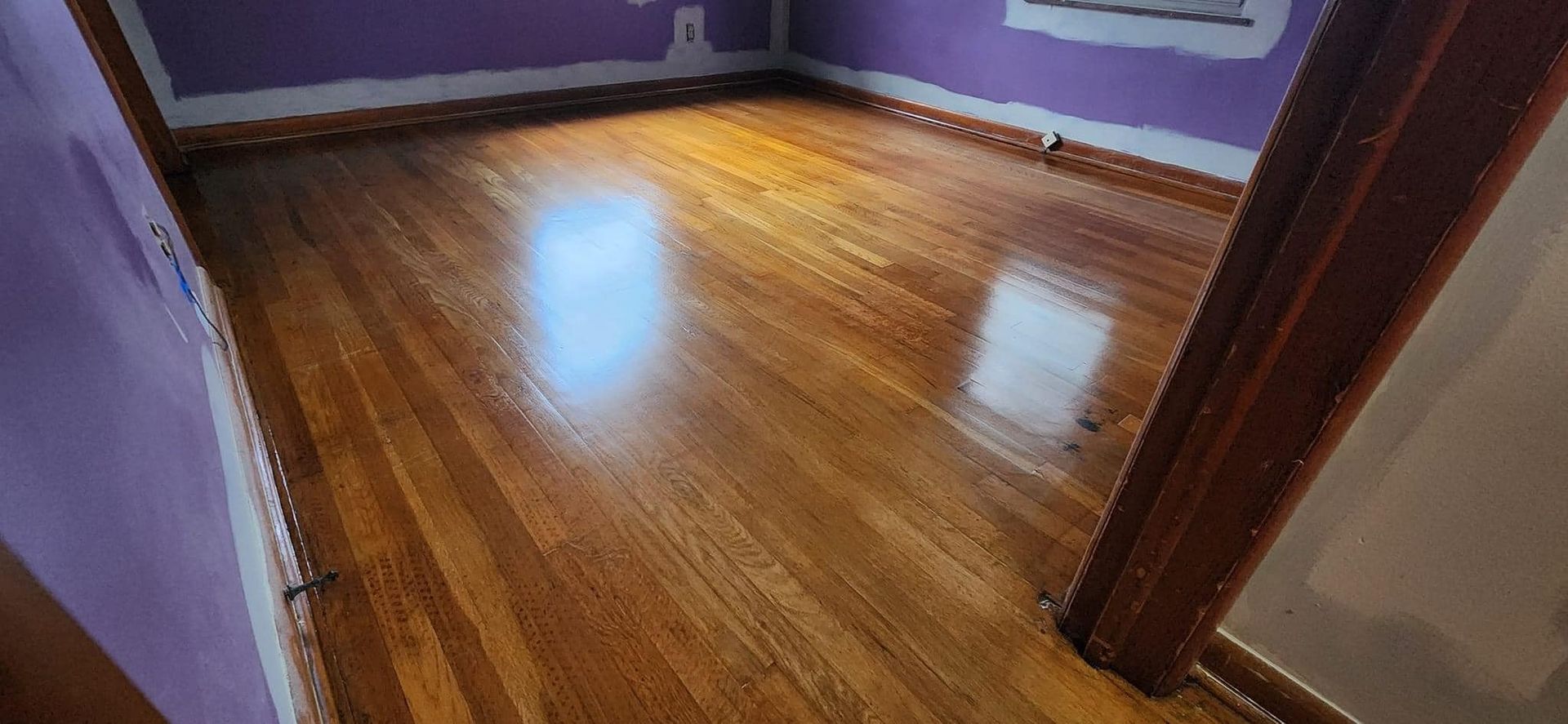 A room with a wooden floor and purple walls.