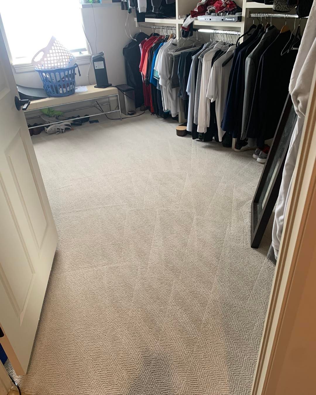 A walk in closet filled with clothes and a window.