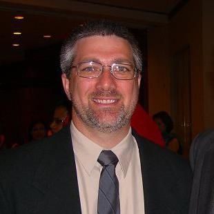A man in a suit and tie is smiling for the camera.