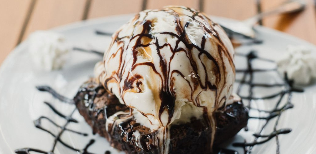 A brownie with ice cream on top of it on a plate.