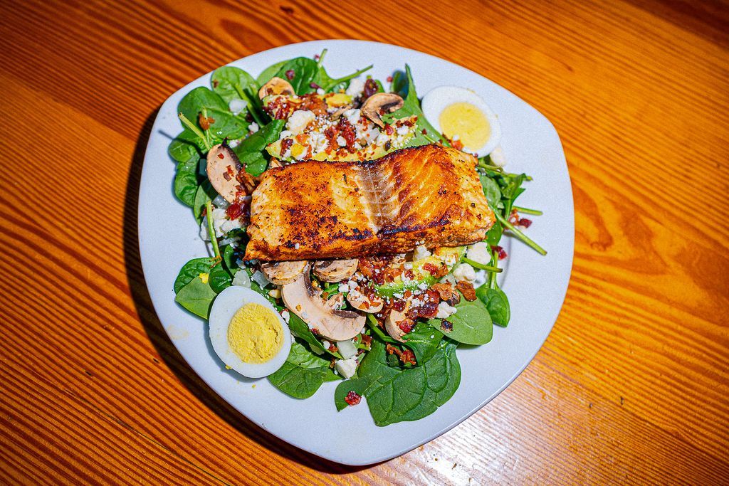 A table topped with plates of food and a glass of wine.