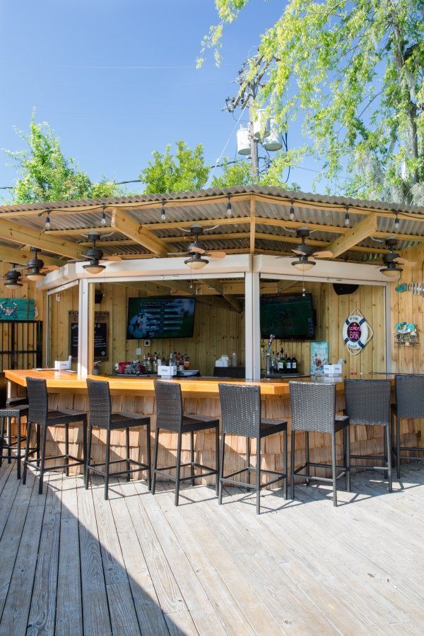 A wooden bar with a lot of chairs and a roof.