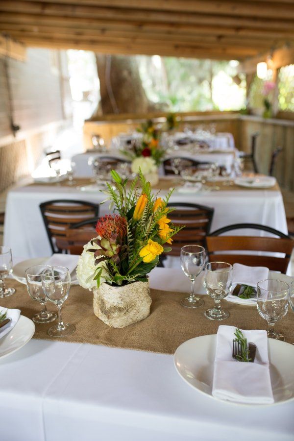 A table set for a wedding reception with a vase of flowers on it.