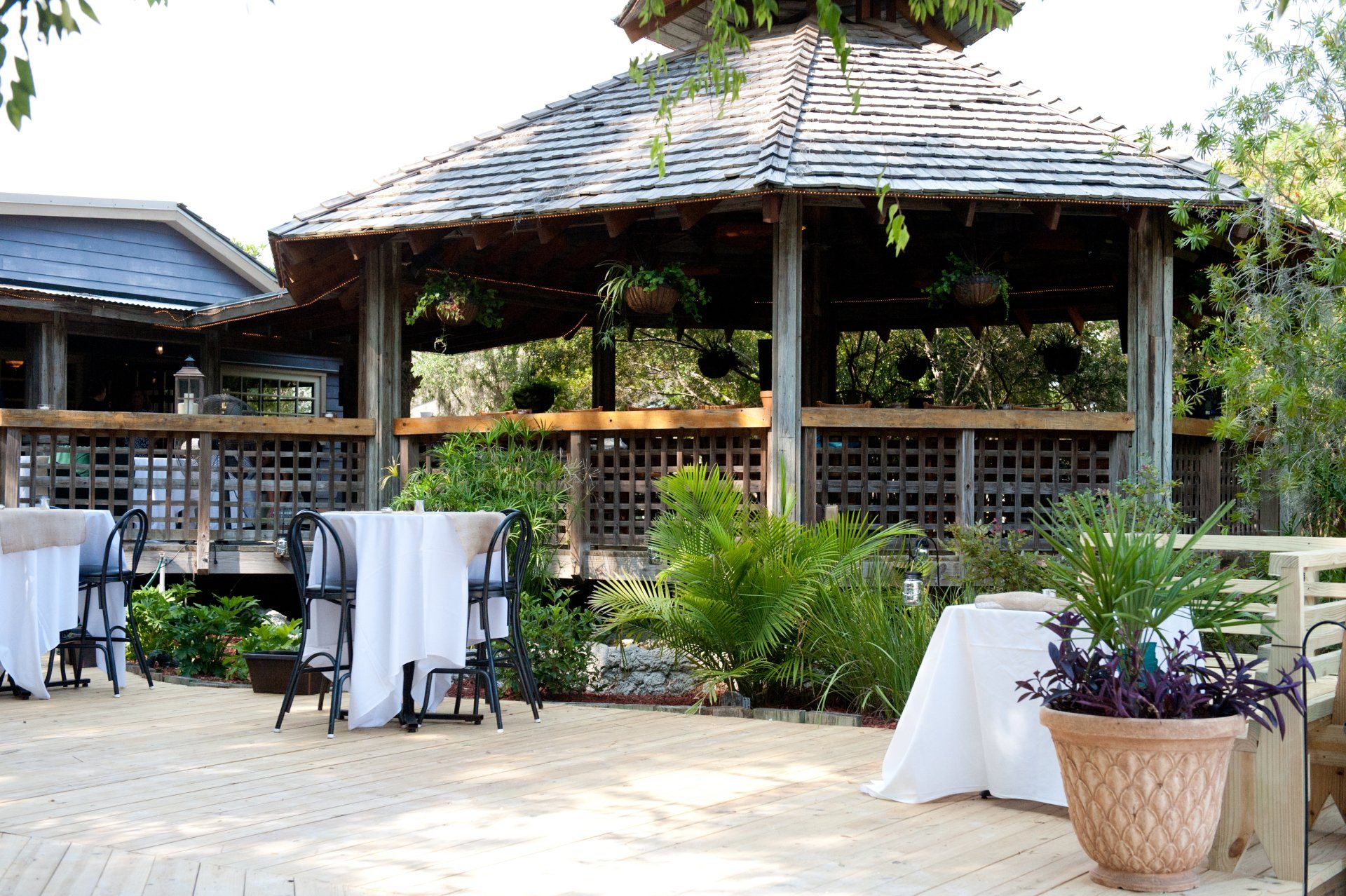 A gazebo with tables and chairs in front of it