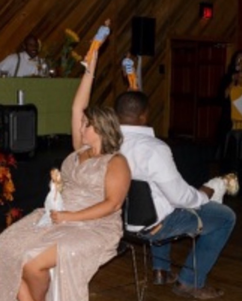 Two people seated back-to-back at a banquet, one holding up a drink in a raised arm.