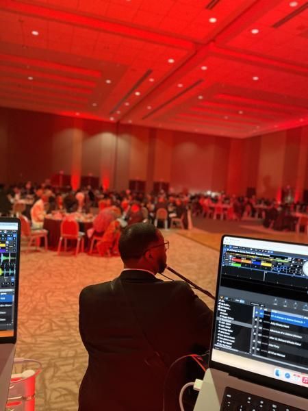 DJ booth overlooking a red-lit banquet hall with seated attendees