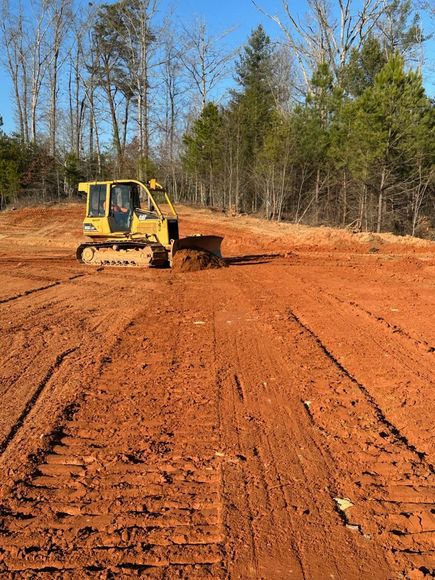 A yellow bulldozer is moving dirt in a backyard.