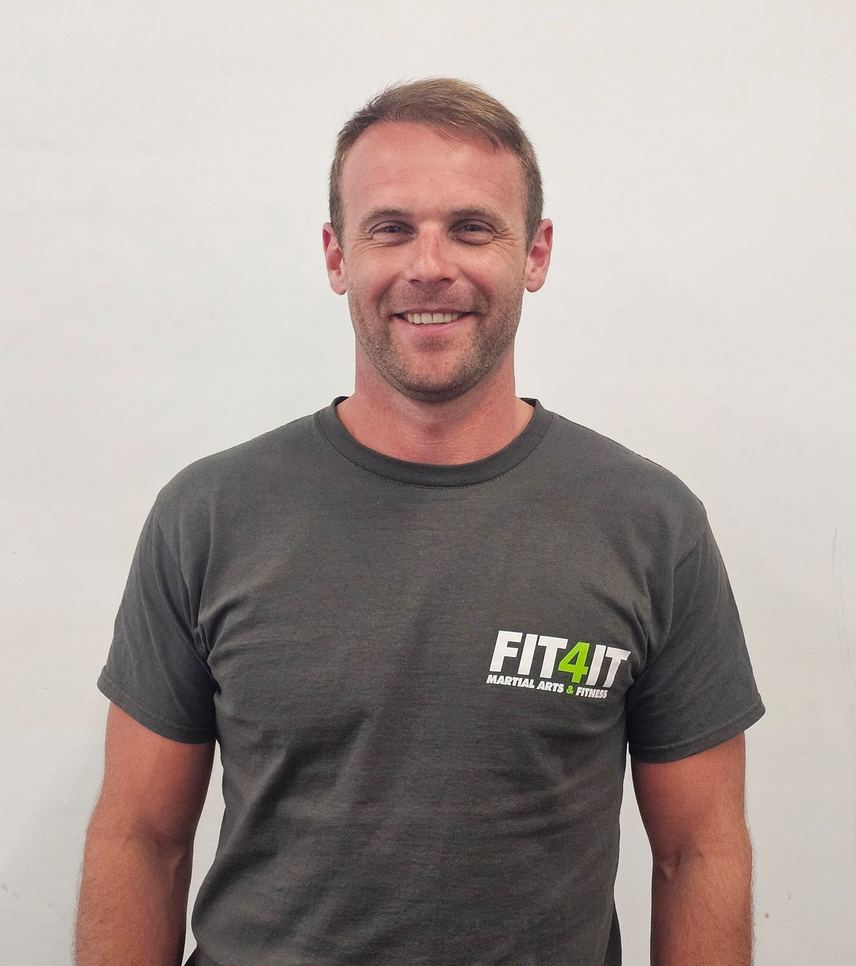 A man wearing a fit4it shirt smiles for the camera